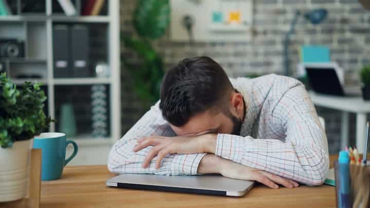 a-man-sitting-at-a-desk-with-his-head-in-his-hands-stress-tired