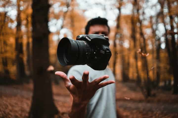black-dslr-camera-floating-over-mans-hand-at-the-woods-photography