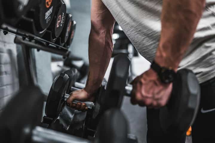 person-in-gray-shirt-holding-black-dumbbell-gym-fitness