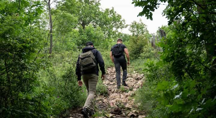 two-men-hiking-up-a-rocky-trail-in-the-woods
